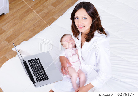 Woman with baby sitting on a bed with laptop - high angle 6276377