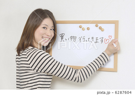 ホワイトボードにメッセージを書く若い女性の写真素材