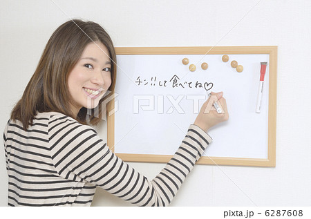 ホワイトボードにメッセージを書く若い女性の写真素材