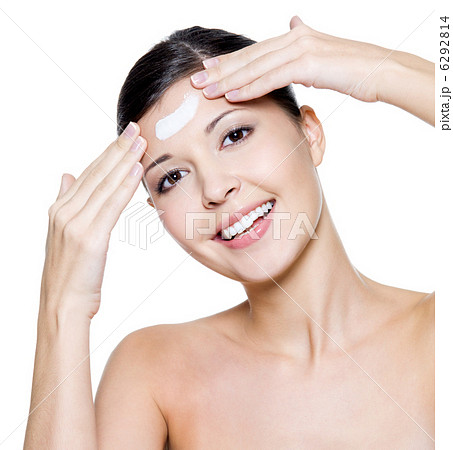 happy woman applying cosmetic cream on forehead happy woman applying cosmetic cream on forehead 6292814
