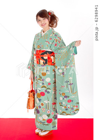 落ち着いた雰囲気の振り袖を着て笑顔で可愛いポーズをする女性の写真素材