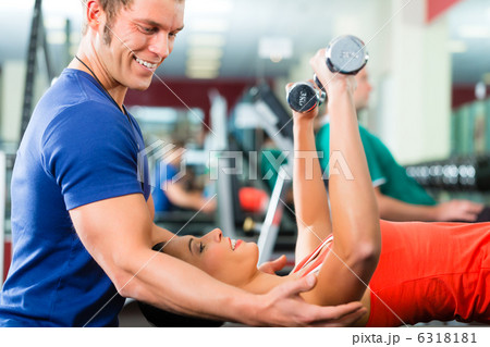 woman and Personal Trainer in gym, with dumbbells 6318181