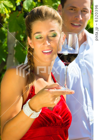 Woman and man standing at vineyard and drinking wine 6320396