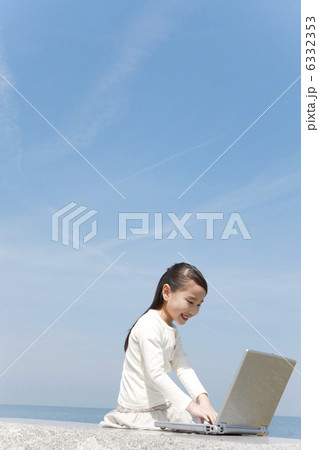 海岸でパソコンを見ている女の子 6332353