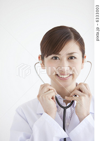 聴診器を耳にあてる笑顔の女医 6333003