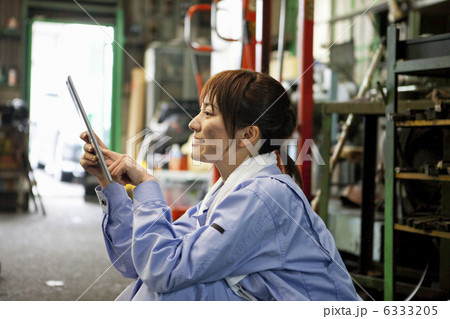 iPadを操作する作業着姿の若者女性 6333205