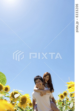 女性をおんぶする男性とヒマワリ畑 6333206