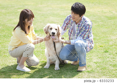 犬を撫でているカップルの写真素材