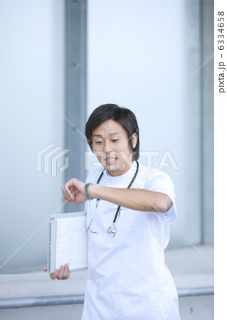 時計を見ながら走っている男性看護師 6334658