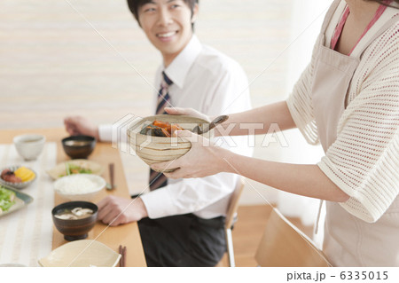 座っている夫と朝食の準備をする妻 6335015