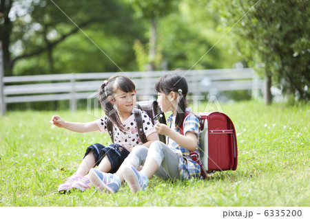 芝生に座っている小学生の女の子2人 6335200