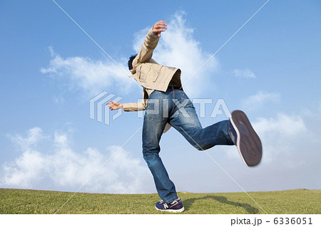 草原を走る男性の後姿の写真素材