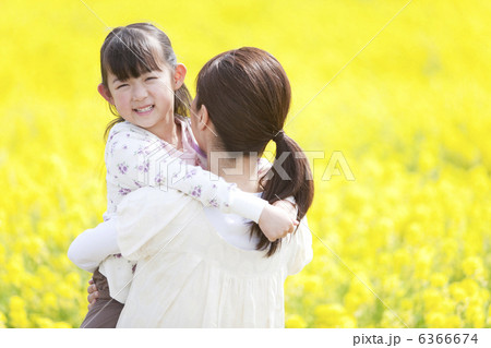 ナノハナ畑で母親に抱っこしてもらう娘 6366674