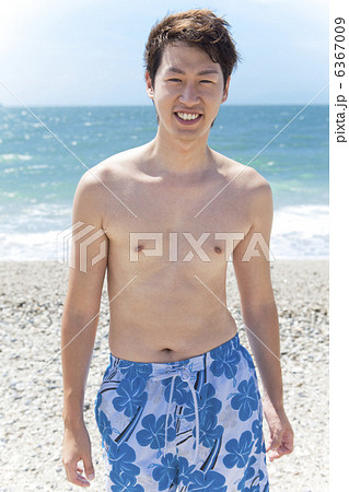 砂浜に立っている笑顔の水着姿の男性 6367009