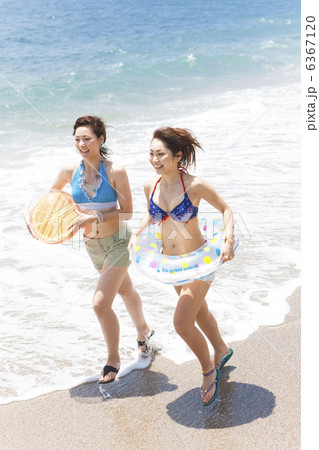 ビーチボールと浮き輪を持って走る女性2人 6367120