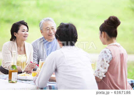 屋外で食事しながら笑顔で会話する4人家族 屋外で食事しながら笑顔で会話する4人家族 6367186