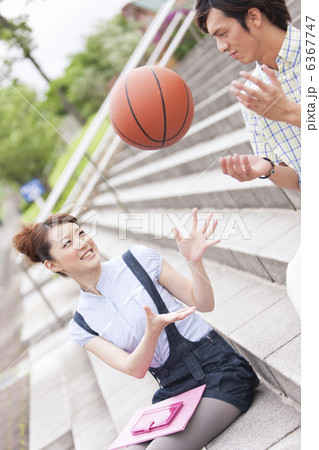 バスケットボールで遊ぶ大学生カップルの写真素材