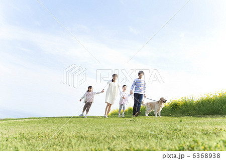 手をつないで歩く4人家族と犬 6368938