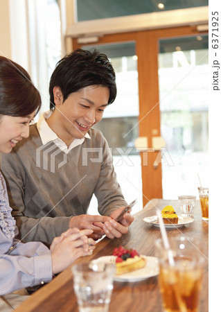 カフェでスマートフォンを見ているカップル カフェでスマートフォンを見ているカップル 6371925