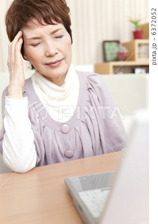 こめかみを押さえている中高年女性 6372052