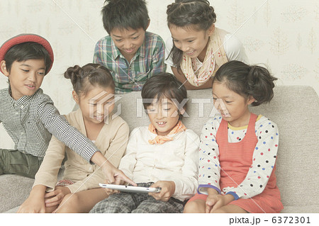 ソファに座る小学生6人とタブレットPC 6372301