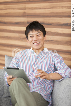座ってiPadを操作する男性 6375283