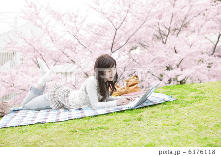 桜とノートパソコンを操作する女性 6376118