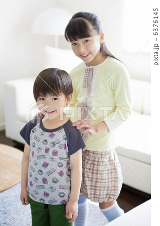 肩に手を置く笑顔の姉と弟 6376145