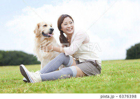 芝生に座っている女性と犬 6376398