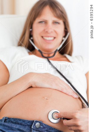 Facing view of an attractive pregnant woman using a stethoscope 6395294