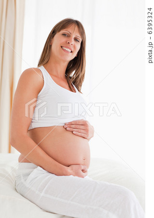 Portrait of a lovely pregnant female posing while sitting on a b Portrait of a lovely pregnant female posing while sitting on a b 6395324