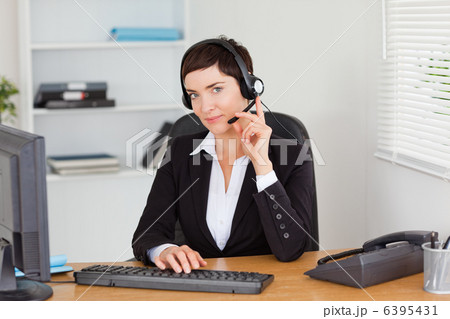 Serious secretary calling with a headset Serious secretary calling with a headset 6395431