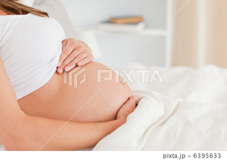 Close-up of a pregnant female lying on a bed 6395633