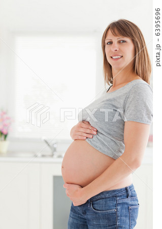 Beautiful pregnant woman posing while caressing her belly Beautiful pregnant woman posing while caressing her belly 6395696