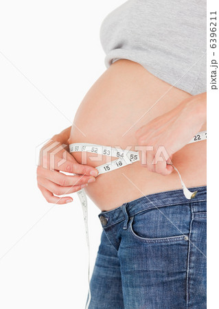 Pregnant woman measuring her belly while standing Pregnant woman measuring her belly while standing 6396211