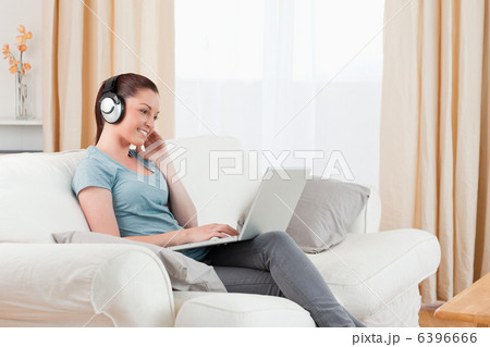 Attractive woman with headphones relaxing with her laptop while 6396666