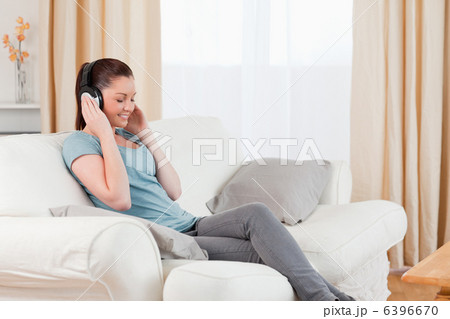 Gorgeous woman relaxing with headphones while sitting on a sofa Gorgeous woman relaxing with headphones while sitting on a sofa 6396670
