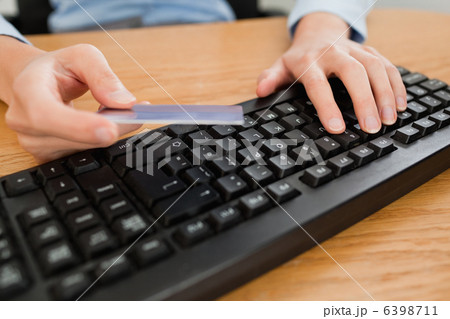 Woman typing on keyboard holding a credit card 6398711