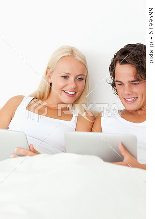 Portrait of a smiling couple using tablet computers 6399599