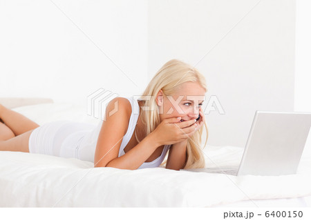 Woman laughing on the phone while using a laptop 6400150