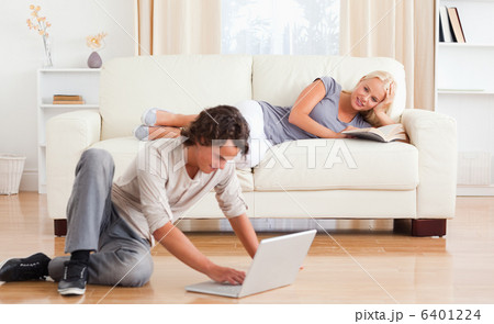 Man using a laptop while his girlfriend is holding a book 6401224