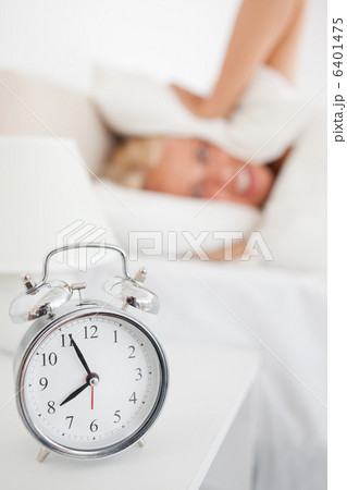 Portrait of a woman hidding her head in a pillow while the alarm Portrait of a woman hidding her head in a pillow while the alarm 6401475