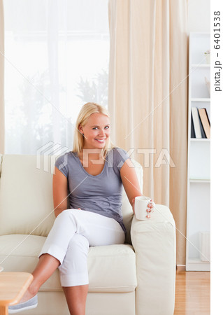 Portrait of a woman sitting on a sofa with a cup of tea 6401538