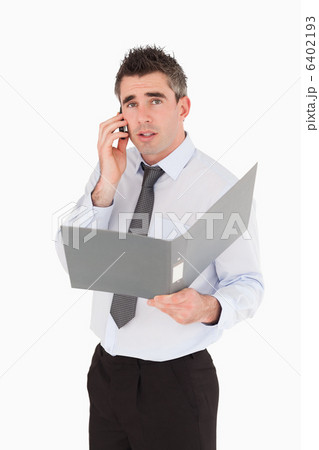 Portrait of a man making a phone call while holding a binder 6402193