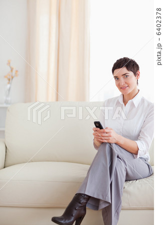 Charming Woman sitting on a sofa with a phone 6402378