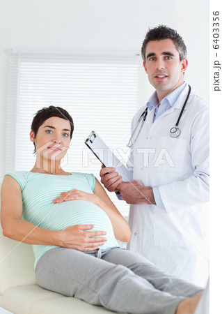 Doctor and pregnant patient looking at the camera Doctor and pregnant patient looking at the camera 6403356
