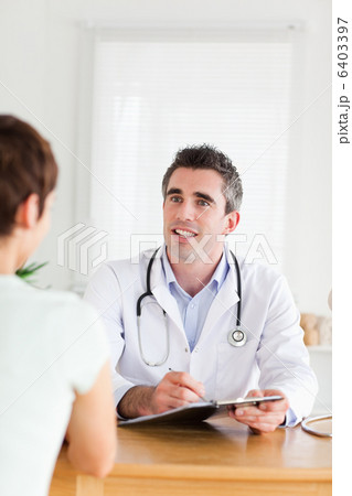 Smiling Doctor talking to a brunette patient 6403397