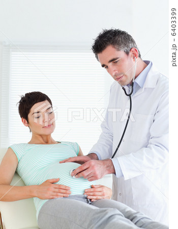 Doctor listening into the belly with a stethoscope 6403399
