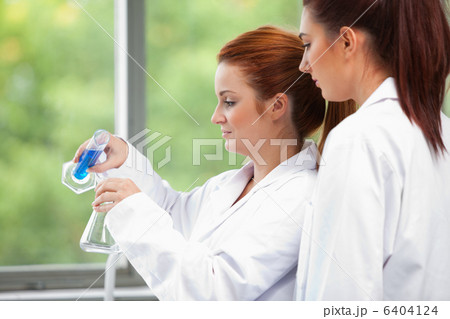 Young scientists pouring liquid in an Erlenmeyer flask 6404124