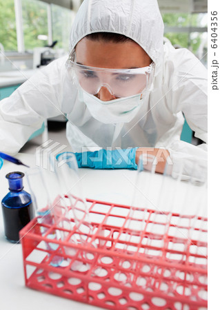 Portrait of a protected female scientist dropping blue liquid in Portrait of a protected female scientist dropping blue liquid in 6404356